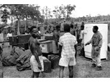 March 1964 : Native porters and locals at Telefomin with some of the equipment from Station 37 ready for loading. The refrigerator ran on kerosene and evey HIRAN ground station had one.
